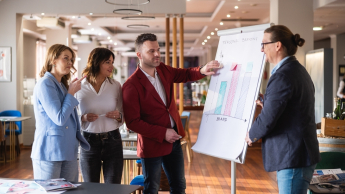 Budowanie i utrzymanie aplikacji no-code | Studia podyplomowe w Opolu | Uniwersytet WSB Merito Opole: Główna grafika: Opole - studia podyplomowe -Budowanie i utrzymanie aplikacji no-code - uczestnicy studiów podyplomowych analizują tresci z flipcharta 