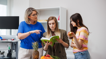 Psychodietetyka i terapia zaburzeń odżywiania | Studia I stopnia w Opolu | Uniwersytet WSB Merito Opole: Główna grafika: Opole - studia II stopnia- Dietetyka: Psychodietetyka i terapia zaburzeń odżywiania- studentki analizują książkę w laboratorium dietetycznym