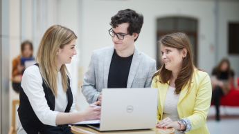 Cross-Border e-Commerce | Studia podyplomowe w Opolu | Uniwersytet WSB Merito Opole: Główna grafika: Opole - studia podyplomowe -Cross-Border e-Commerce- uczestnicy studiów podyplomowych rozmawiają miedzy sobą na korytarzu z otwartym laptopem na stoliku