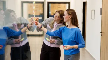 Zarządzanie jakością | Studia podyplomowe w Opolu | Uniwersytet WSB Merito Opole: Główna grafika: Opole - studia podyplomowe - Zarządzanie jakością - uczestniczki studiów podyplomowych naklejają karteczki samoprzylepne na szybę
