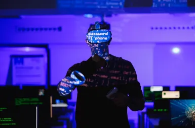 Laboratoria i pracownie | Uniwersytet WSB Merito Opole: Pracownia VR, student z okularami VR i kontrolerami stoi w sali komputerowej