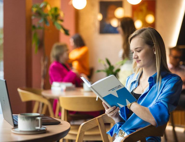 Kosmetologia | Studia I stopnia w Opolu | Uniwersytet WSB Merito Opole: Dziewczyna siedząca w kawiarni, czyta notatki