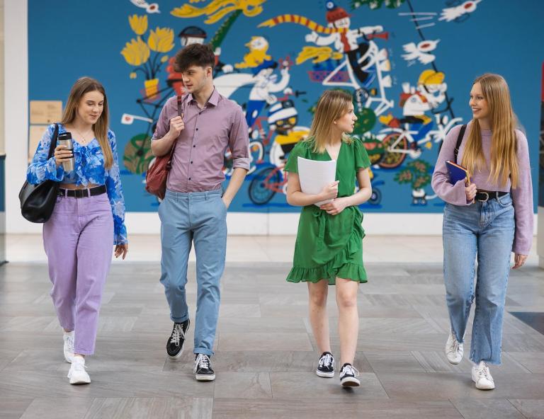 Praca z osobami niedostosowanymi społecznie z profilaktyką uzależnień | Studia I stopnia w Opolu | Uniwersytet WSB Merito Opole: na zdjęciu grupa studentów, przechadzająca się po holu uczelni 