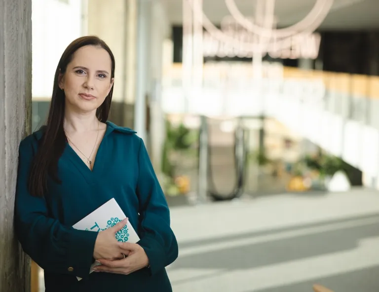 Dialog motywujący | Studia podyplomowe w Opolu | Uniwersytet WSB Merito Opole: Kobieta w zielonej koszuli, w dłoniach trzyma książkę