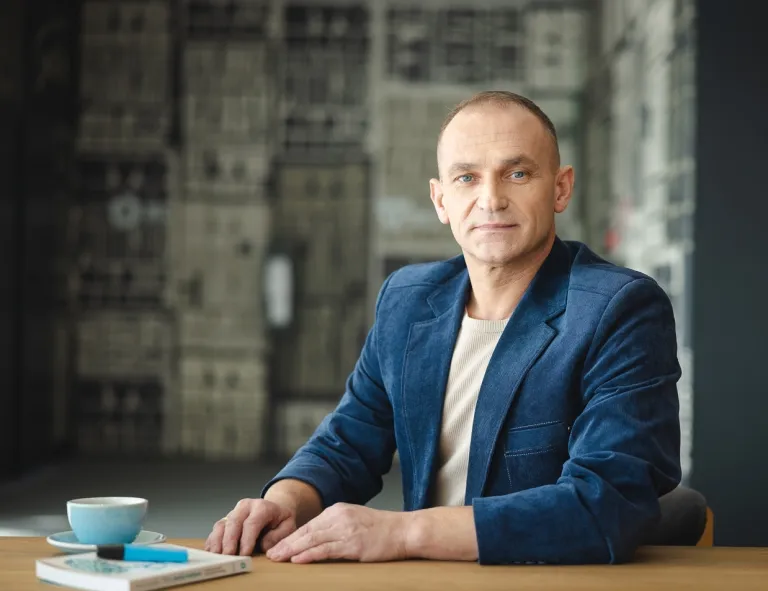 Audyt wewnętrzny i controlling | Studia podyplomowe w Opolu | Uniwersytet WSB Merito Opole: Mężczyzna siedzący w kawiarni, na stole stoi kubek i notes