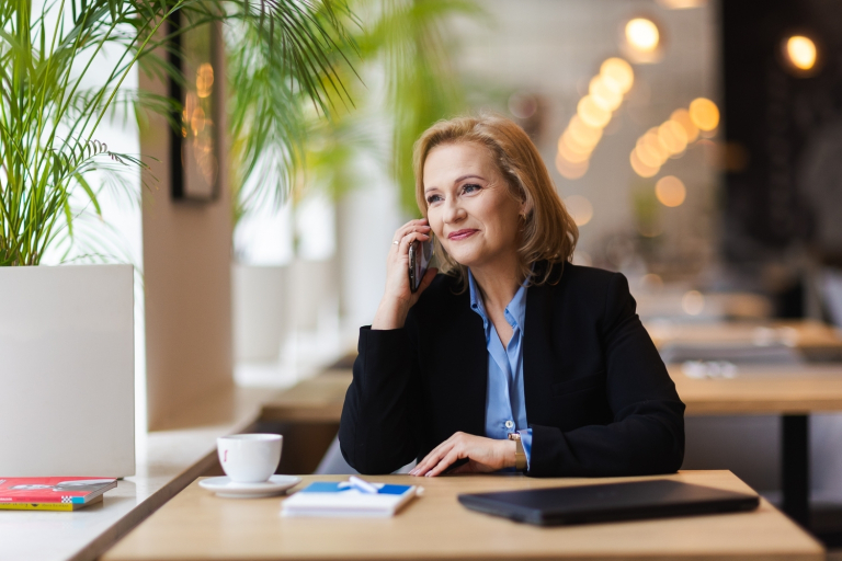 Analiza i informatyka śledcza, studia podyplomowe: kobieta rozmawia przez telefon przy biurko na którym leży komputer