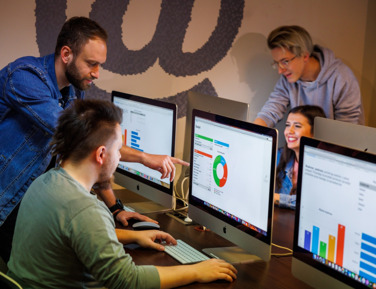 Finanse i rachunkowość | Studia II stopnia ze studiami podyplomowymi w Opolu | Uniwersytet WSB Merito Opole: Grupa osób pracująca na komputerach, na ekranach wyświetlają się kolorowe wykresy i dane