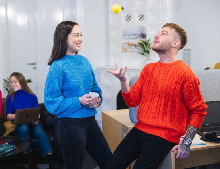 Psychologia i zarządzanie kapitałem ludzkim | Studia II stopnia ze studiami podyplomowymi  | Uniwersytet WSB Merito Opole: Grupa osób w biurze, na pierwszym planie mężczyzna podrzucający w dłoni żółtą piłkę