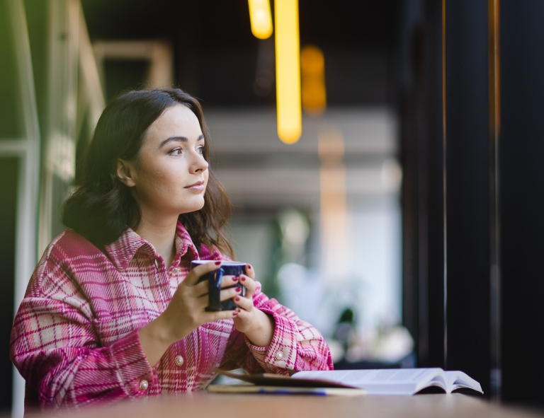 Trychologia z elementami biokosmetologii i fitoterapii | Studia I stopnia w Opolu | Uniwersytet WSB Merito Opole: Studentka siedzi przy biurku z filiżanką kawy w ręce