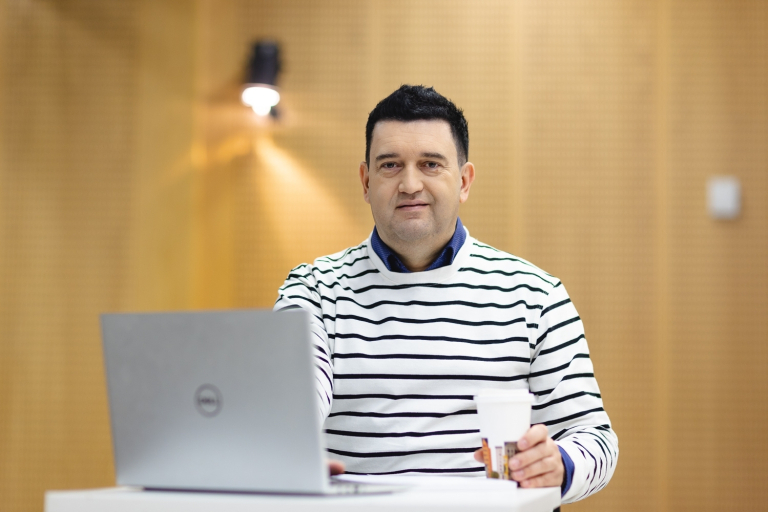 Inżynieria sieci, systemów i bezpieczeństwa IT | Studia I stopnia w Opolu | Uniwersytet WSB Merito Opole: Student stoi przy biurku z otwartym laptopem