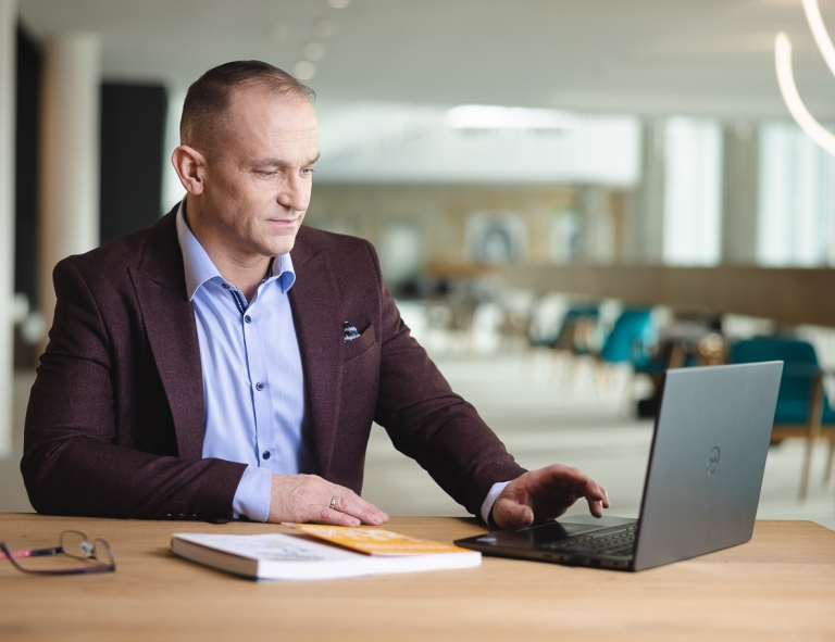 Zamówienia publiczne | Studia podyplomowe w Opolu | Uniwersytet WSB Merito Opole: Uczestnik studiów podyplomowych siedzi przy biurku i zagląda w laptopa