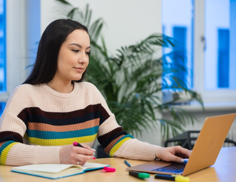 Pedagogika opiekuńczo-wychowawcza z pedagogiką Montessori | Studia I stopnia w Opolu | Uniwersytet WSB Merito Opole: Studentka siedzi przy biurku z laptopem