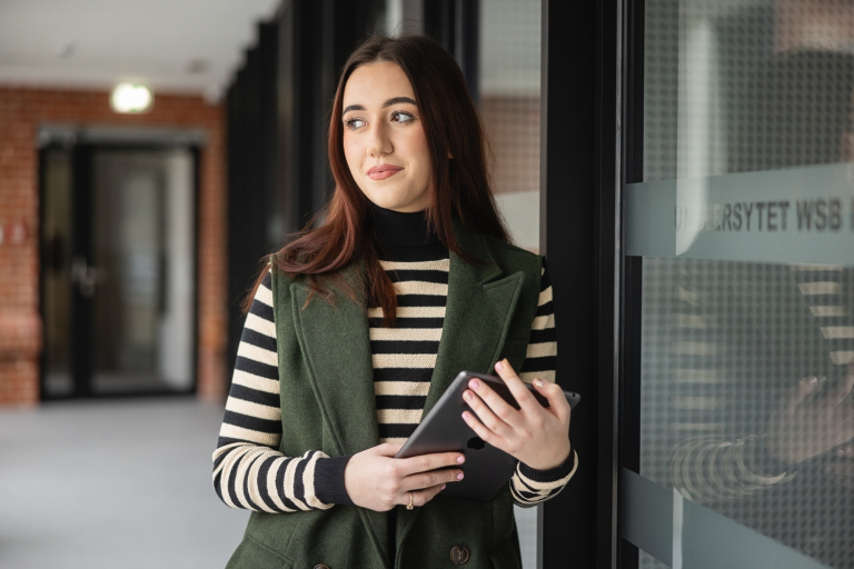 Sztuczna inteligencja i Data Science | Studia I stopnia w Opolu | Uniwersytet WSB Merito Opole: Studentka stoi i opiera się o ścianę