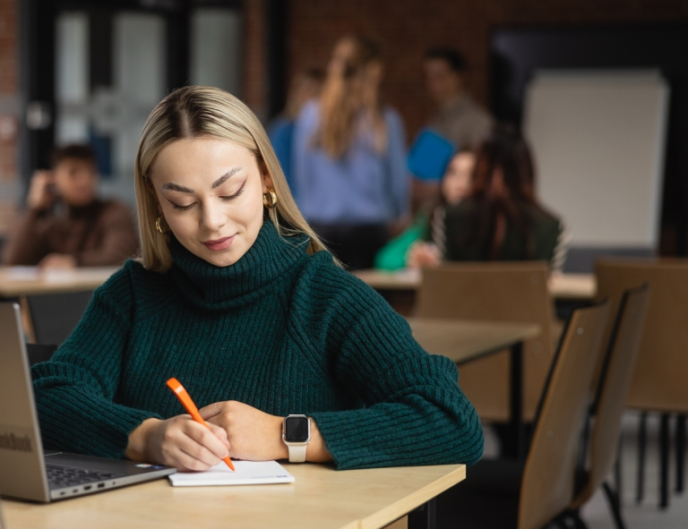 Dietetyka sportowa | Studia II stopnia ze studiami podyplomowymi  | Uniwersytet WSB Merito Opole: Uczestniczka studiów podyplomowych siedząca przy biurku z laptopem.