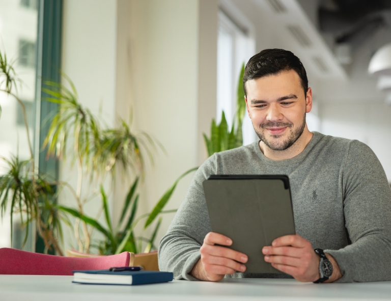 Projektowanie gier komputerowych | Studia podyplomowe w Opolu | Uniwersytet WSB Merito Opole: Uczestnik studiów podyplomowych siedzi przy biurku i pracuje na laptopie