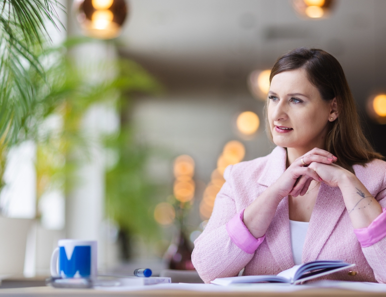 Księgowość i płace w przedsiębiorstwie | Studia podyplomowe w Opolu | Uniwersytet WSB Merito Opole: Uczestniczka studiów podyplomowych robi notatki siedząc przy biurku