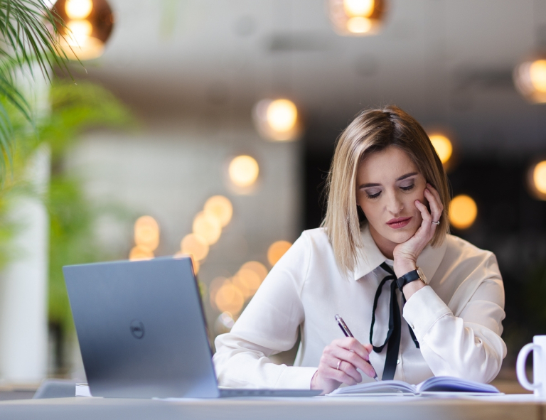 Analiza i informatyka śledcza | Studia podyplomowe w Opolu | Uniwersytet WSB Merito Opole: Uczestniczka studiów podyplomowych siedząca przy biurku z laptopem i robiąca notatki