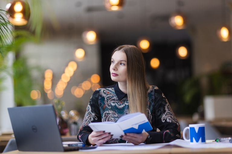 Wykorzystanie zarządzania kryzysowego, obrony cywilnej i cyberbezpieczeństwa w planowaniu i zapobieganiu atakom terrorystycznym | Studia podyplomowe w Opolu | Uniwersytet WSB Merito Opole: Uczestniczka studiów podyplomowych siedząca przy biurku z laptopem i robiąca notatki