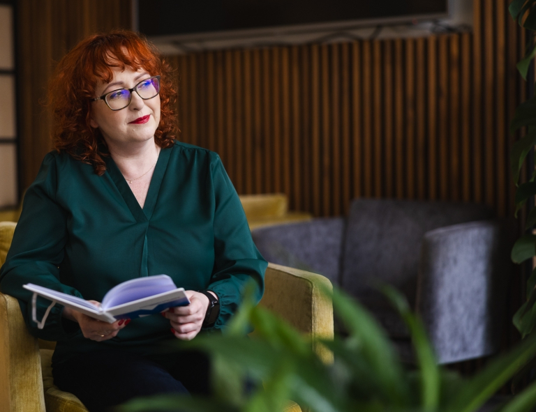 Projektowanie Ekologiczne i Architektura Zieleni (Eco Design) | Studia podyplomowe w Opolu | Uniwersytet WSB Merito Opole: Uczestniczka studiów podyplomowych siedzi przy stoliku i czyta książkę