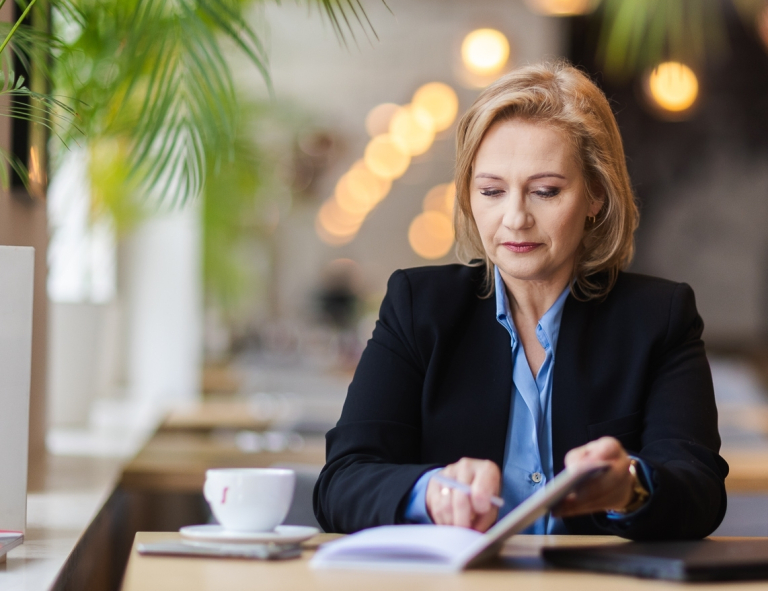 Zarządzanie finansami w przedsiębiorstwie | Studia podyplomowe w Opolu | Uniwersytet WSB Merito Opole: Uczestniczka studiów podyplomowych robi notatki siedząc przy biurku