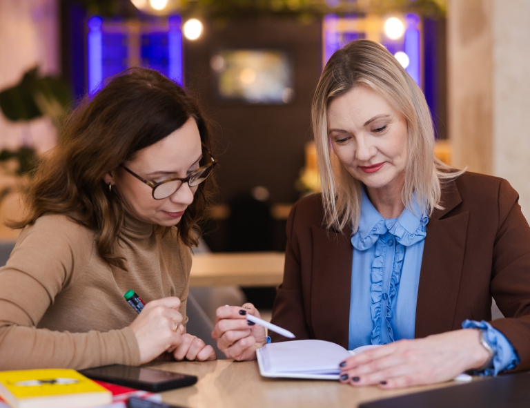 Zarządzanie i automatyzacja procesów w biznesie | Studia podyplomowe w Opolu | Uniwersytet WSB Merito Opole: Uczestniczki studiów podyplomowych siedzą przy biurku i rozmawiają 