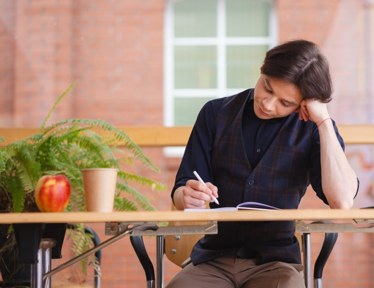 Dietetyka | Studia II stopnia w Opolu | Uniwersytet WSB Merito Opole: Student siedzi przy biurku i robi notatki