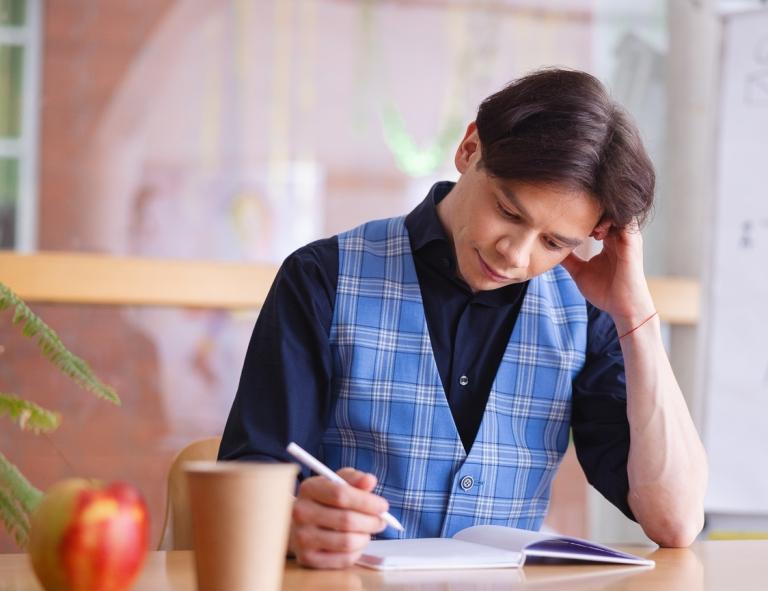 Neurodietetyka | Studia podyplomowe w Opolu | Uniwersytet WSB Merito Opole: Uczestnik studiów podyplomowych siedzi przy biurku i robi notatki