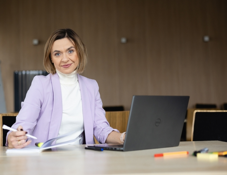 Wykorzystanie zarządzania kryzysowego, obrony cywilnej i cyberbezpieczeństwa w planowaniu i zapobieganiu atakom terrorystycznym | Studia podyplomowe w Opolu | Uniwersytet WSB Merito Opole: Uczestniczka studiów podyplomowych siedząca przy biurku z laptopem i robiąca notatki