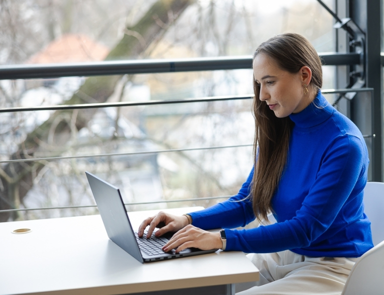 E-commerce i zarządzanie platformami sprzedażowymi | Studia podyplomowe w Opolu | Uniwersytet WSB Merito Opole: Uczestniczka studiów podyplomowych siedząca przy biurku z laptopem.
