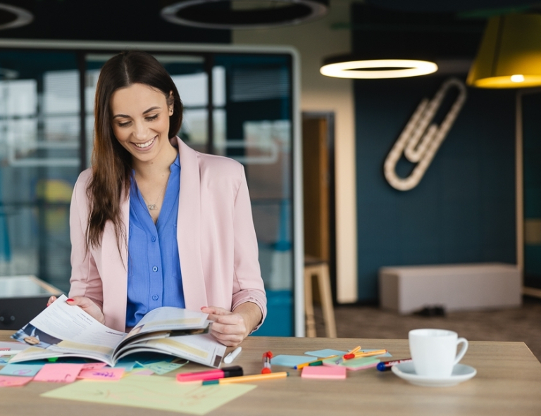 Psychoonkologia | Studia podyplomowe w Opolu | Uniwersytet WSB Merito Opole: Uczestniczka studiów podyplomowych siedzi przy biurku i czyta książkę