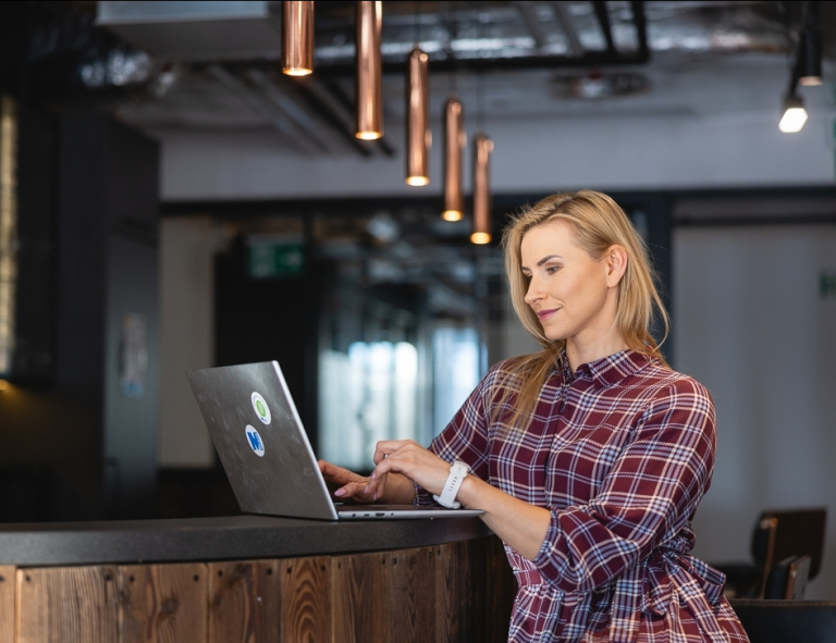 Budowanie i utrzymanie aplikacji no-code | Studia podyplomowe w Opolu | Uniwersytet WSB Merito Opole: Uczestniczka studiów podyplomowych siedząca przy biurku z laptopem.