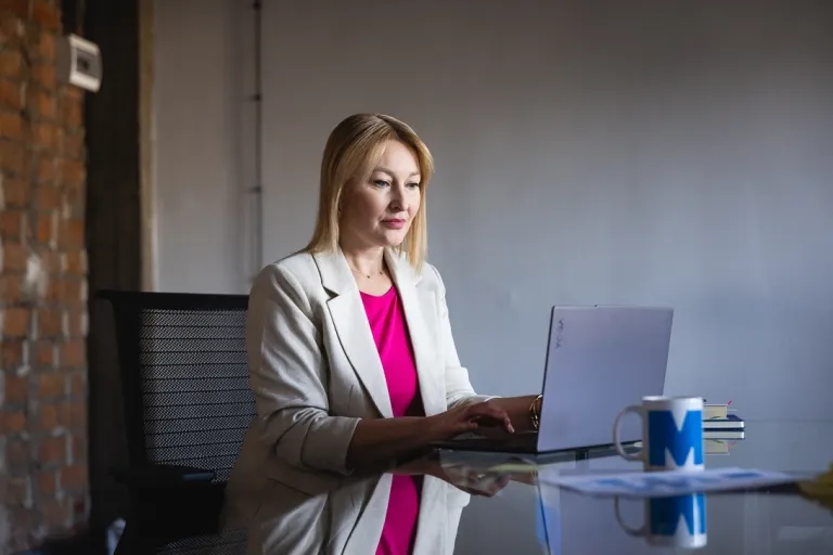 Zarządzanie jakością i produkcją w branży produkcyjnej | Studia podyplomowe w Opolu | Uniwersytet WSB Merito Opole: Uczestniczka studiów podyplomowych siedzi przy biurku i pracuje przy laptopie