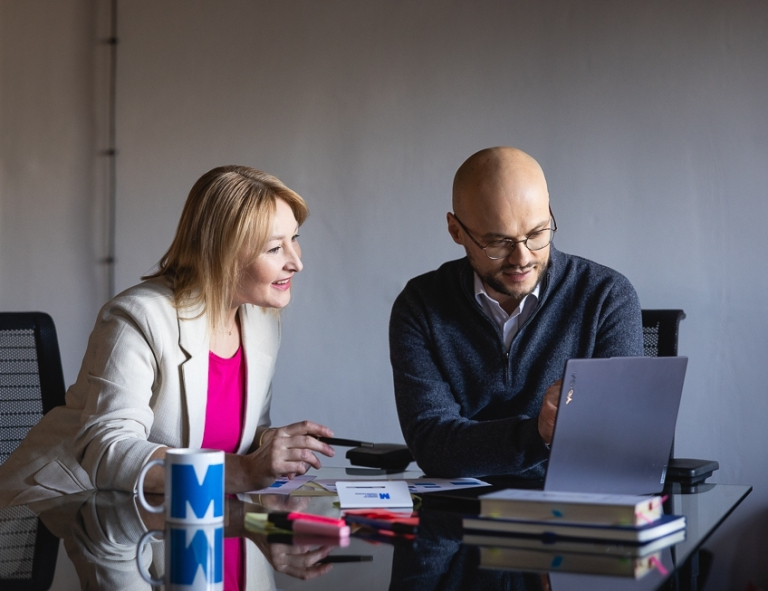 Studia menedżerskie | Studia podyplomowe w Opolu | Uniwersytet WSB Merito Opole: Uczestnicy studiów podyplomowych siedzą i rozmawiają, analizujac treści z laptopa