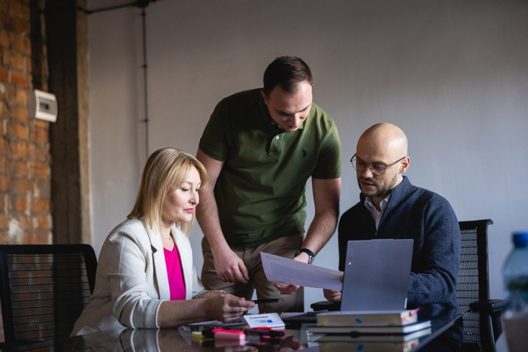 Cyberbezpieczeństwo, studia podyplomowe: Uczestnicy studiów podyplomowych siedzą przy laptopie i analizują treści