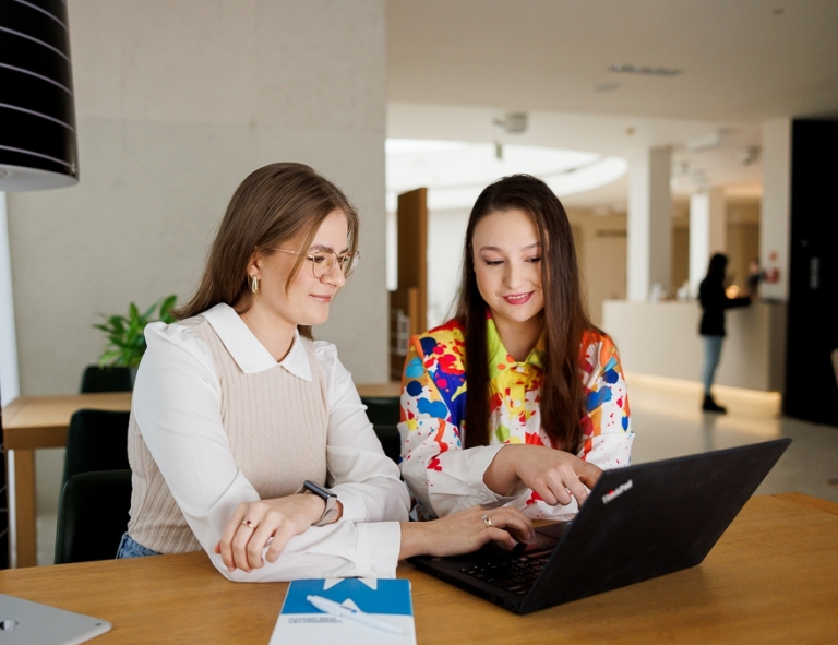 Kadry i płace, studia podyplomowe: Uczestniczki studiów podyplomowych siedzą przy biurku i rozmawiają 