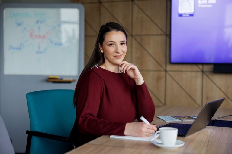 Zastosowanie AI w biznesie dla menedżerów | Studia podyplomowe w Opolu | Uniwersytet WSB Merito Opole: Uczestniczka studiów podyplomowych siedzi przy biurku z otwarty laptopem i sporządza notatki