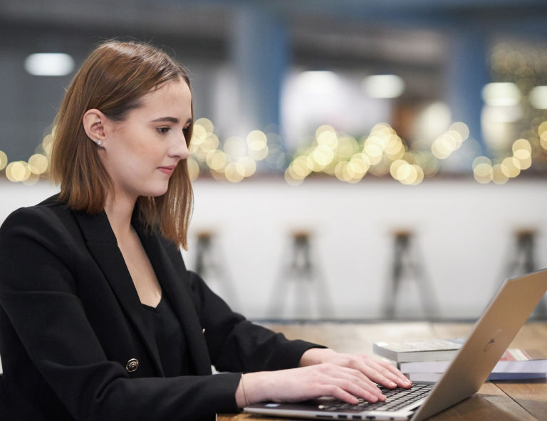 Product Manager w erze AI - zarządzanie produktami cyfrowymi | Studia podyplomowe w Opolu | Uniwersytet WSB Merito Opole: Uczestniczka studiów podyplomowych siedzi przy biurku i pracuje przy laptopie