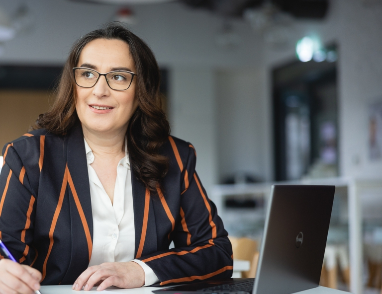 Programista Python Developer | Studia podyplomowe w Opolu | Uniwersytet WSB Merito Opole: Uczestniczka studiów podyplomowych siedząca przy biurku z laptopem.