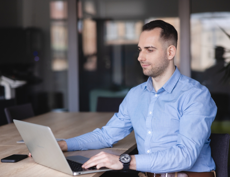 Sztuczna inteligencja (AI) z elementami cyberpsychologii | Studia podyplomowe w Opolu | Uniwersytet WSB Merito Opole: Uczestnik studiów podyplomowych siedzi przy biurku i pracuje na laptopie