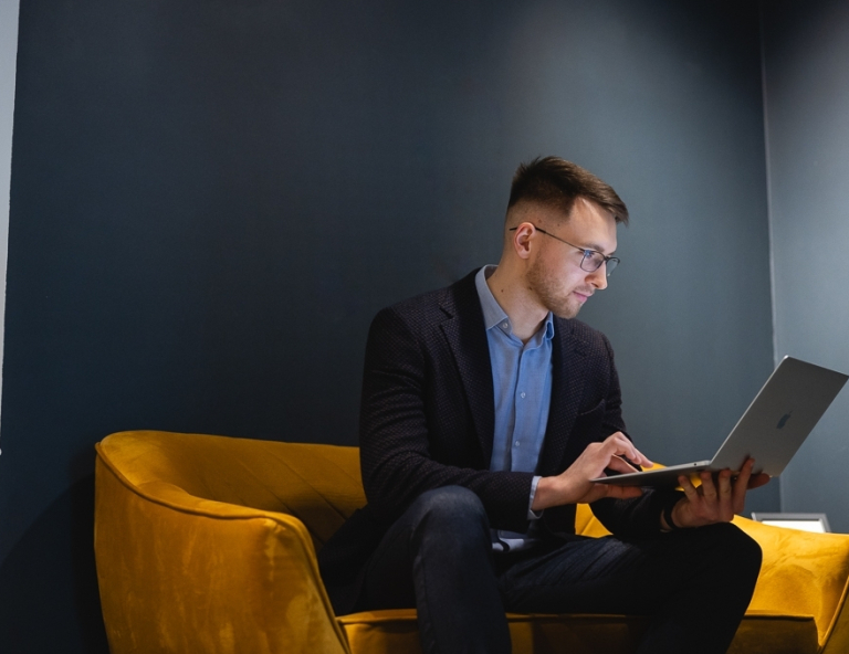 Wycena nieruchomości | Studia podyplomowe w Opolu | Uniwersytet WSB Merito Opole: Uczestnik studiów podyplomowych siedzi  i pracuje na laptopie