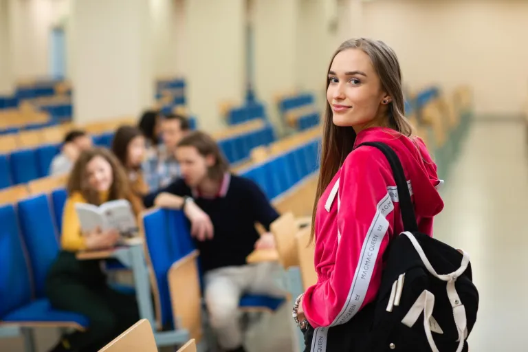 Pedagogika opiekuńczo-wychowawcza z neuropedagogiką | Uniwersytet WSB Merito Opole: Młoda dziewczyna patrzy w obiektyw a tle widać grupę dziewcząt