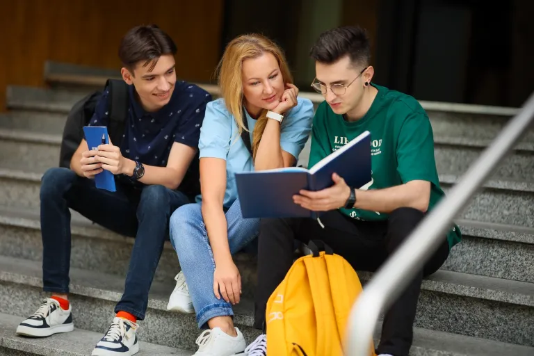 Finanse i rachunkowość | Studia II stopnia ze studiami podyplomowymi w Opolu | Uniwersytet WSB Merito Opole: Grupa osób siedzących na schodach, przeglądają wspólnie notatki