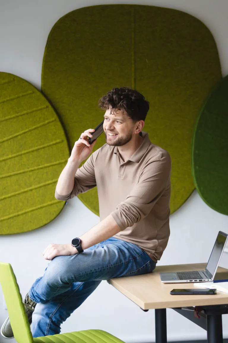 International Management | Uniwersytet WSB Merito Opole: Mężczyzna siedzący na biurku, rozmawia przez telefon