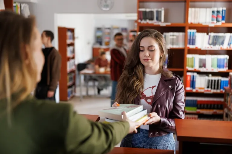 Psychodietetyka i terapia zaburzeń odżywiania | Uniwersytet WSB Merito Opole: Studentka odbiera książkę z biblioteki