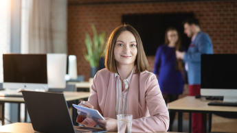 Podatki i doradztwo podatkowe | Studia podyplomowe w Poznaniu | Uniwersytet WSB Merito w Poznaniu: Kobieta przy laptopie, pracująca w nowoczesnej przestrzeni biurowej.