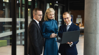 Menedżer ds. czystości technicznej | Uniwersytet WSB Merito w Poznaniu: uczestnicy MBA patrzący na laptopa na korytarzu uczelni- Uniwersytet WSB Merito Poznań