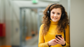 Marketing w cyfrowej transformacji (Sales in Innovative Enterprise) | Studia II stopnia ze studiami podyplomowymi  | Uniwersytet WSB Merito w Poznaniu: Studentka WSB Merito Poznań słucha muzyki na korytarzu uczelni