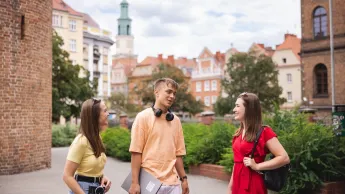 Outsourcing rozwiązań chmurowych | Studia II stopnia w Poznaniu | Uniwersytet WSB Merito w Poznaniu: 2 dziewczyny i chłopak rozmawiają w centrum miasta Poznania