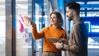 E-biznes | Studia I stopnia w Poznaniu | Uniwersytet WSB Merito w Poznaniu: Studenci omawiają projekt przy tablicy z notatkami