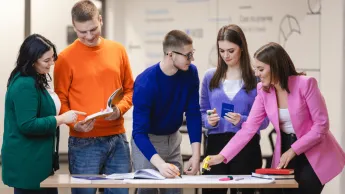 Bezpieczeństwo wewnętrzne | Studia I stopnia w Poznaniu | Uniwersytet WSB Merito w Poznaniu: Grupa studentów wspólnie pracuje nad materiałami przy stole
